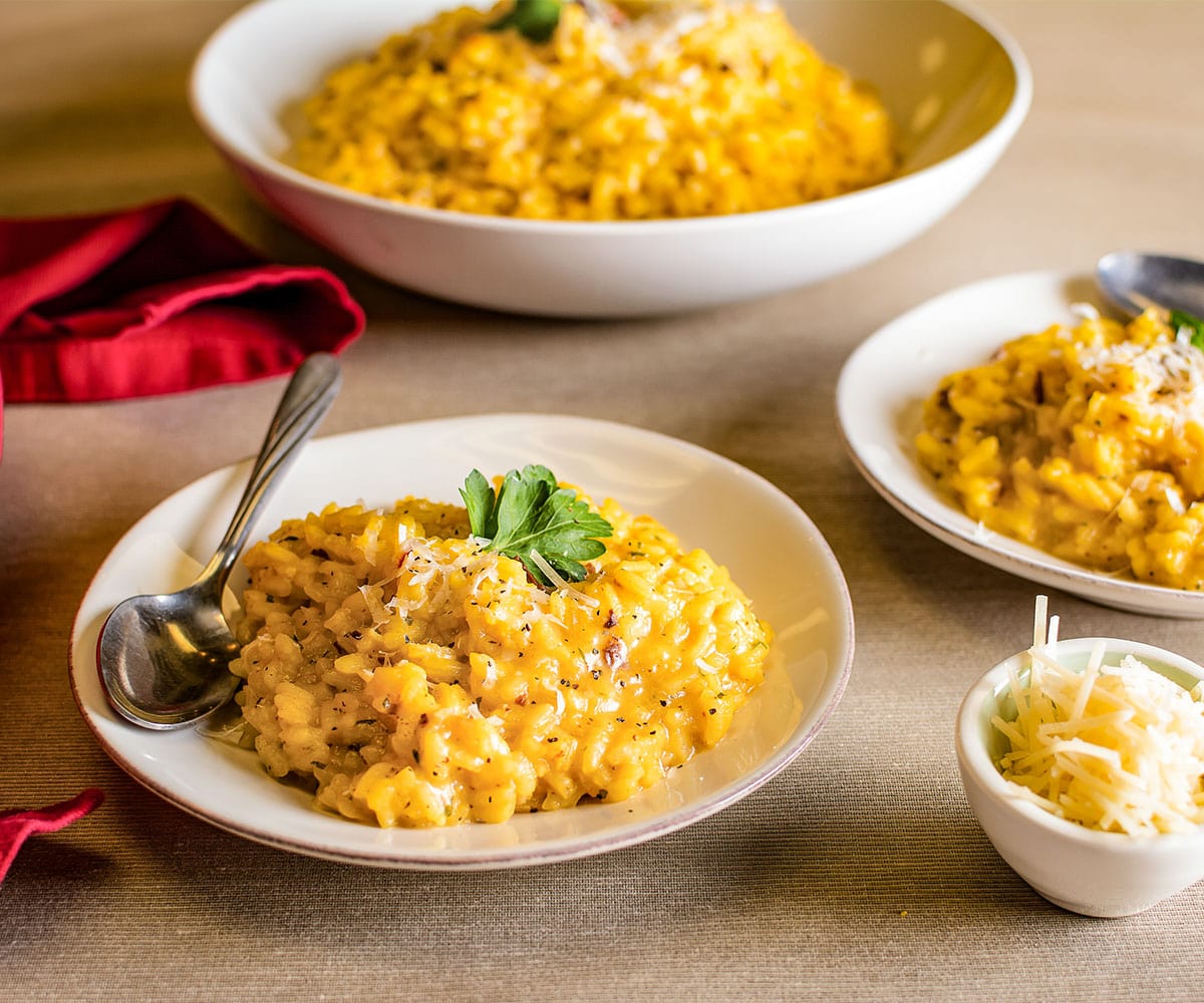 table setting with a plate of saffron & chanterelle risotto garnished with shaved cheese